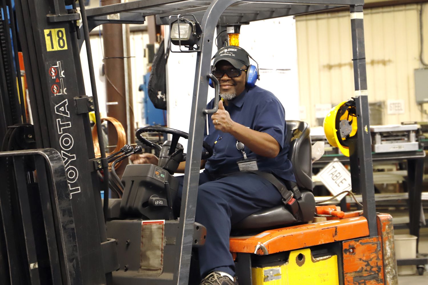 Phoenix Specialty Mfg. Co. staff member giving thumbs up to camera as he operates a forklift