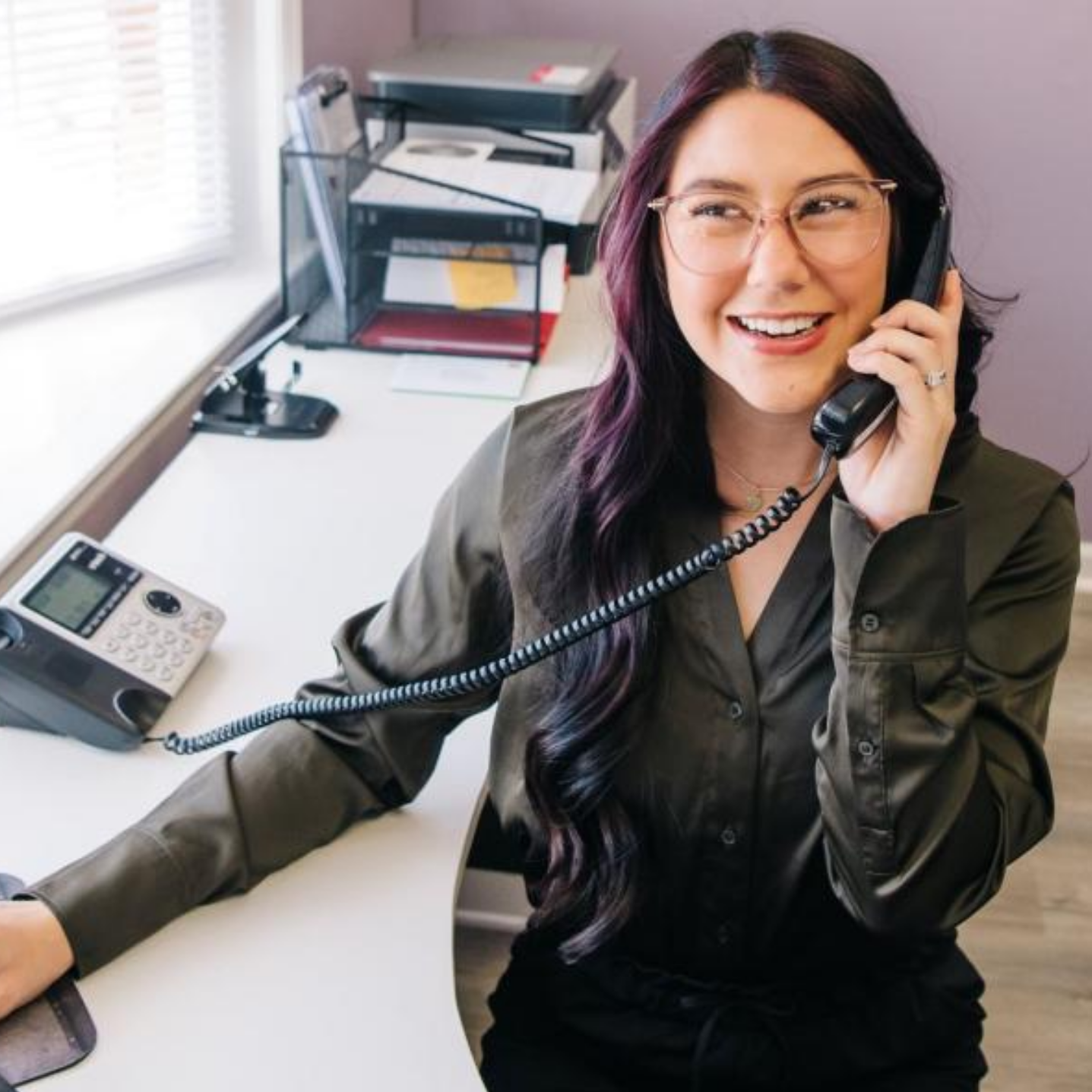 Photo of Cornerstone Family Chiropractic staff member working at desk and answering the telephone.