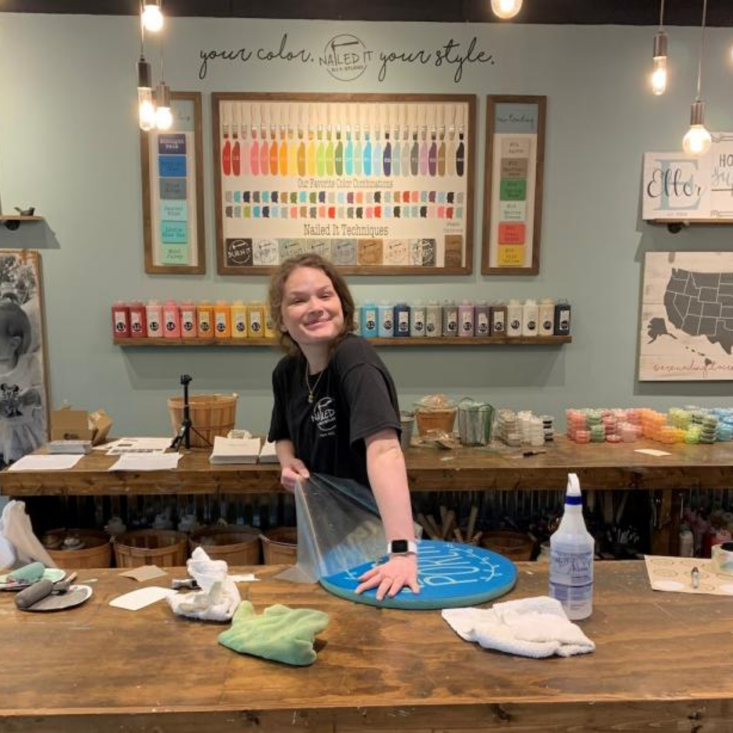 Staff member smiling at camera as she unwraps crafted sign at studio work table