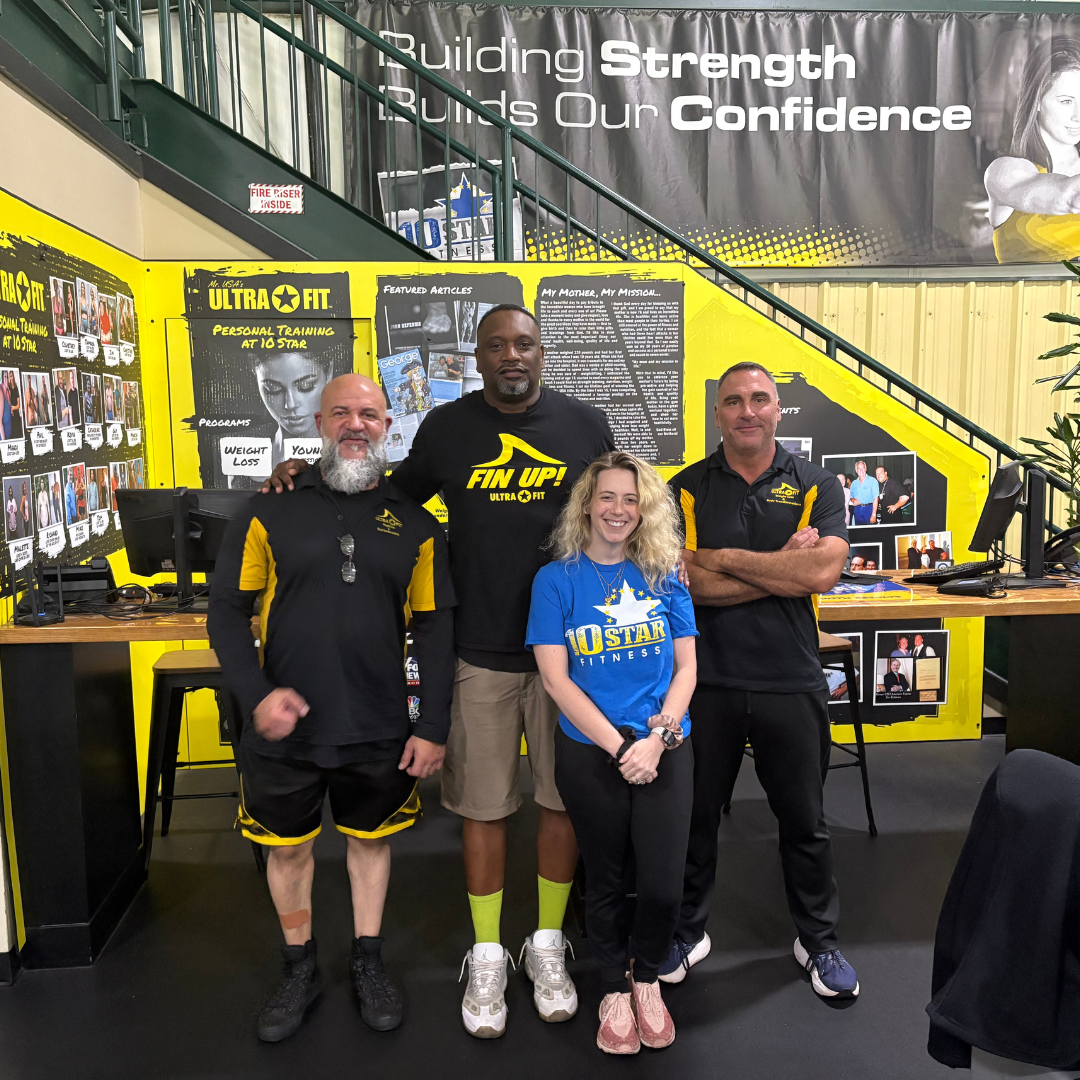Group of fitness staff standing in their gym, posing for picture. 