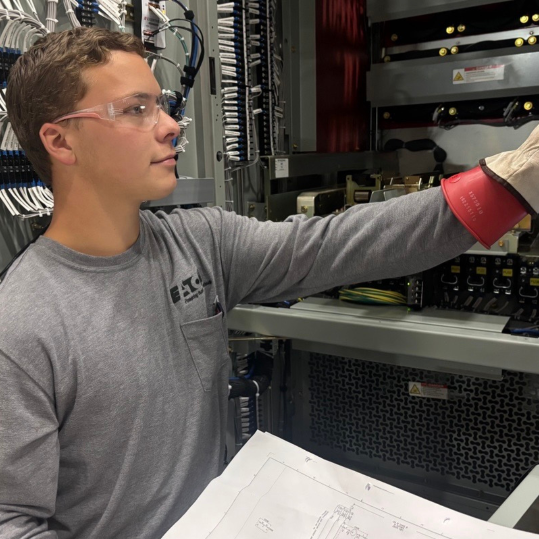 A man is holding a piece of paper, extending his left hand to operate electric system