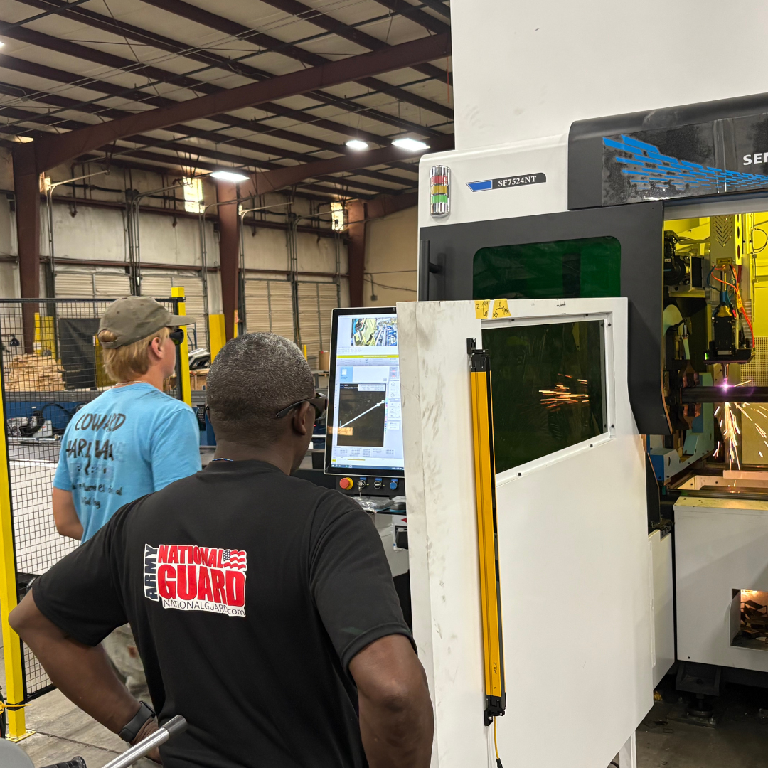 Two men stand looking at a screen at their work