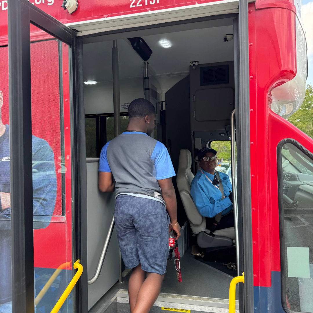 A man walks onto a bus, greeting the bus driver
