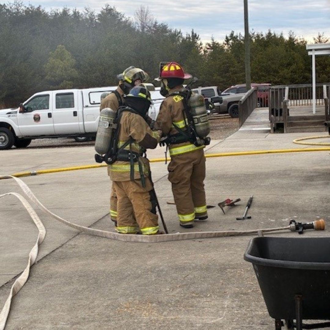 Three fire fighters gather outside on the pavement