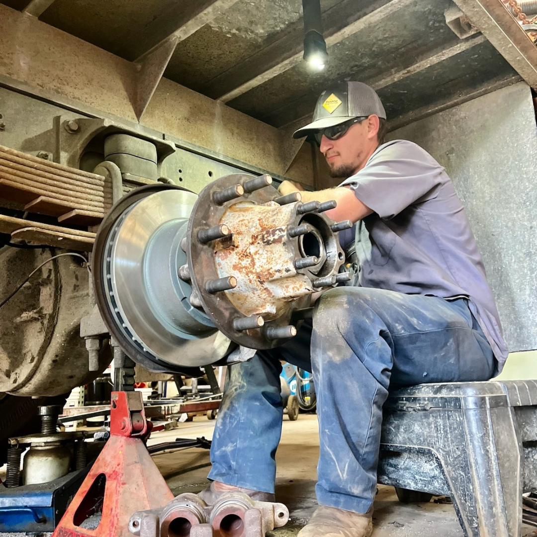 A man works, sitting on a bench, works construction in a tight space