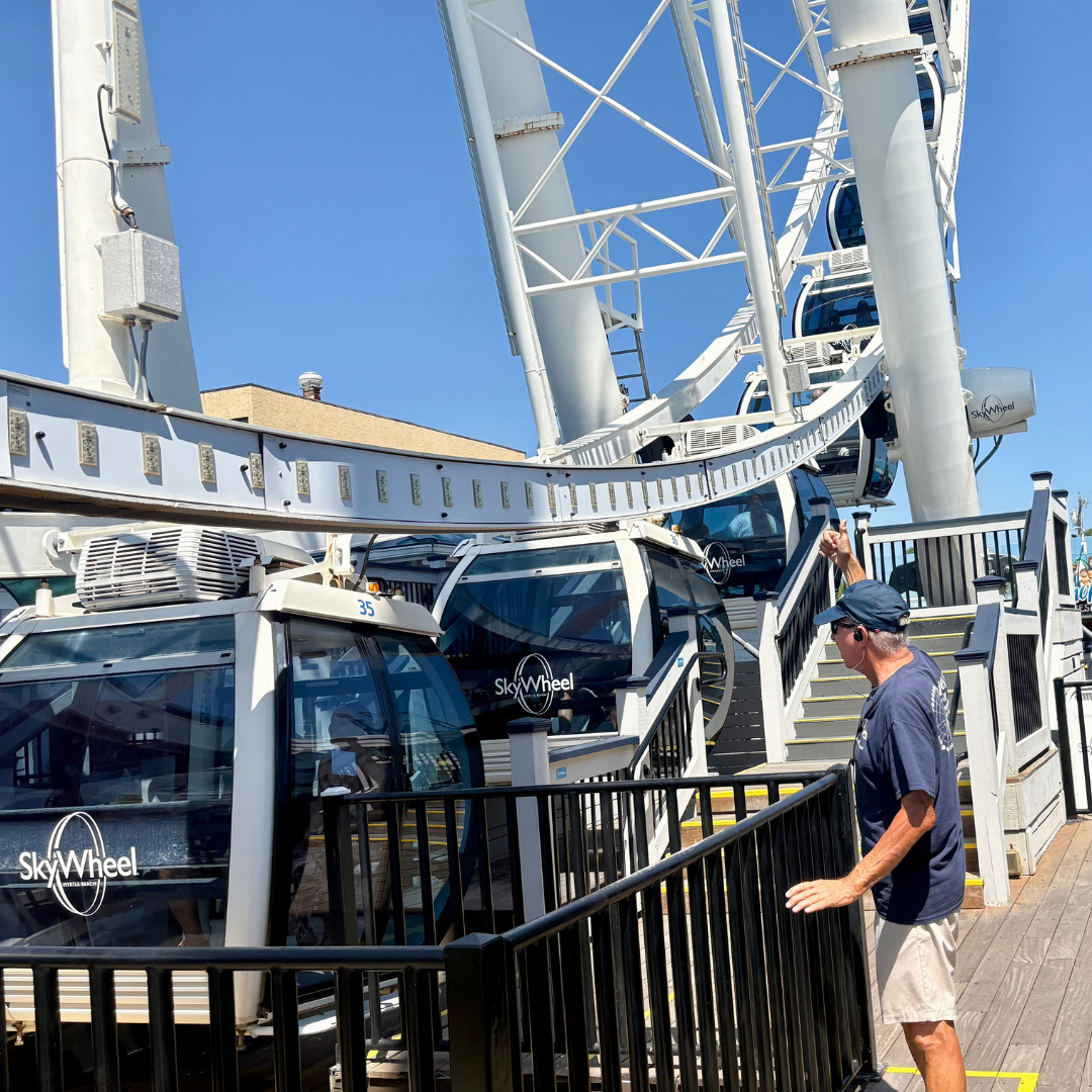 The picture shows the bottom of the skywheel while a worker standing at the bottom helps people get on