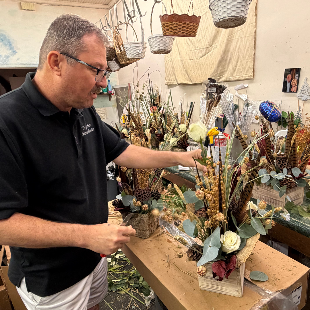 A man behind a table works on assorting and assembling a bouquet 