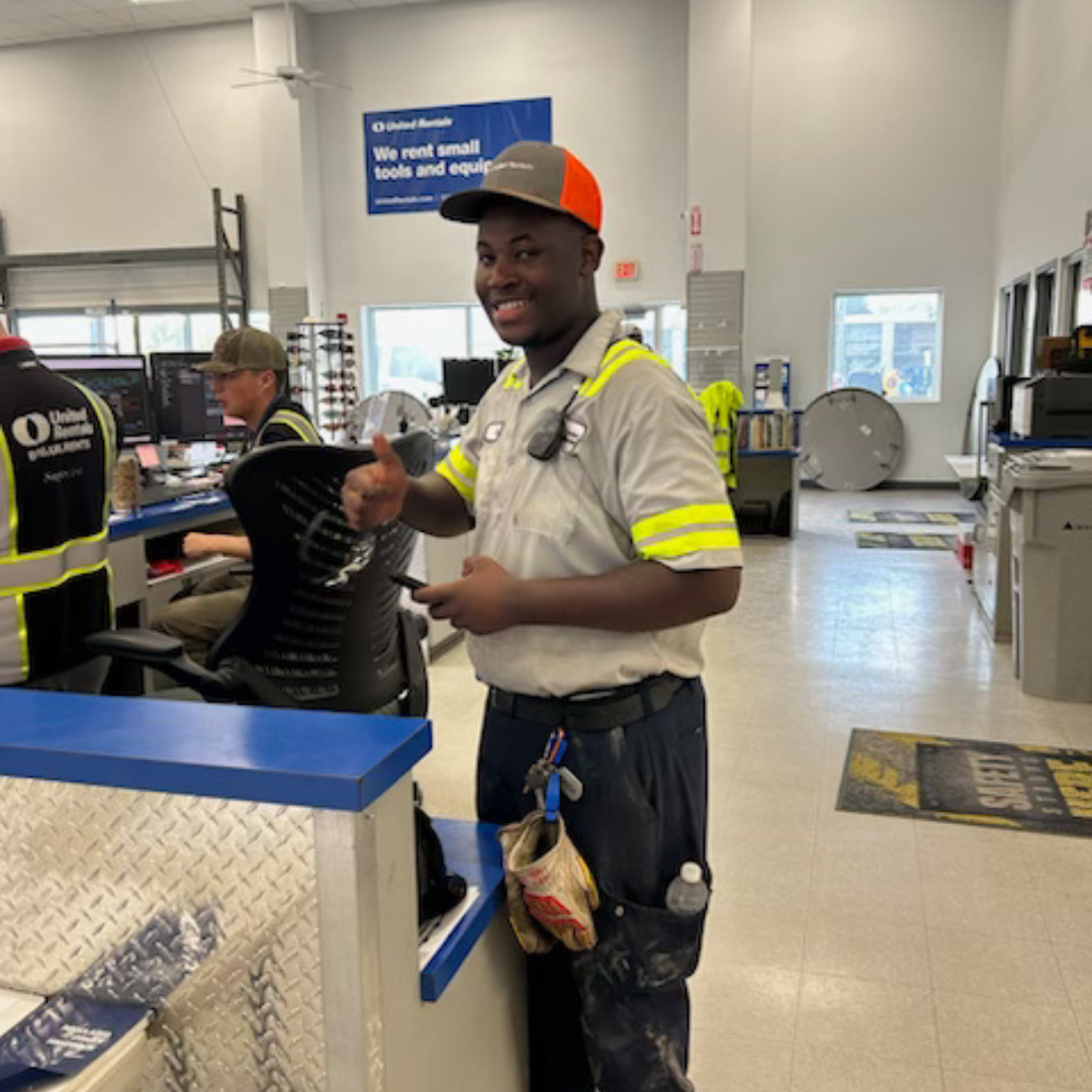 A man in his uniform smiles and holds up a thumbs up at the camera