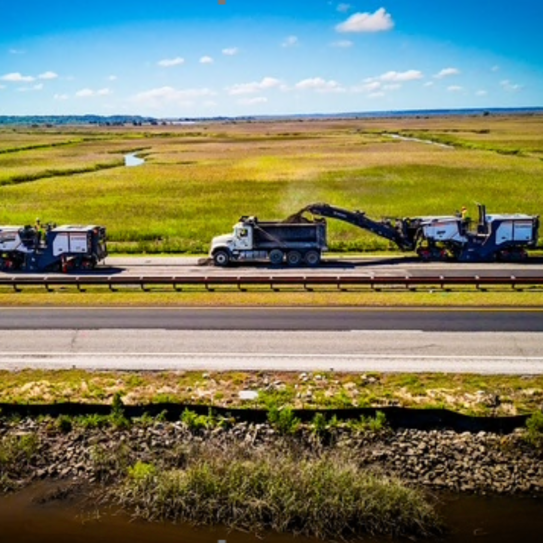 On the highway, on the side of the road there are two big machinery and a dump truck between them
