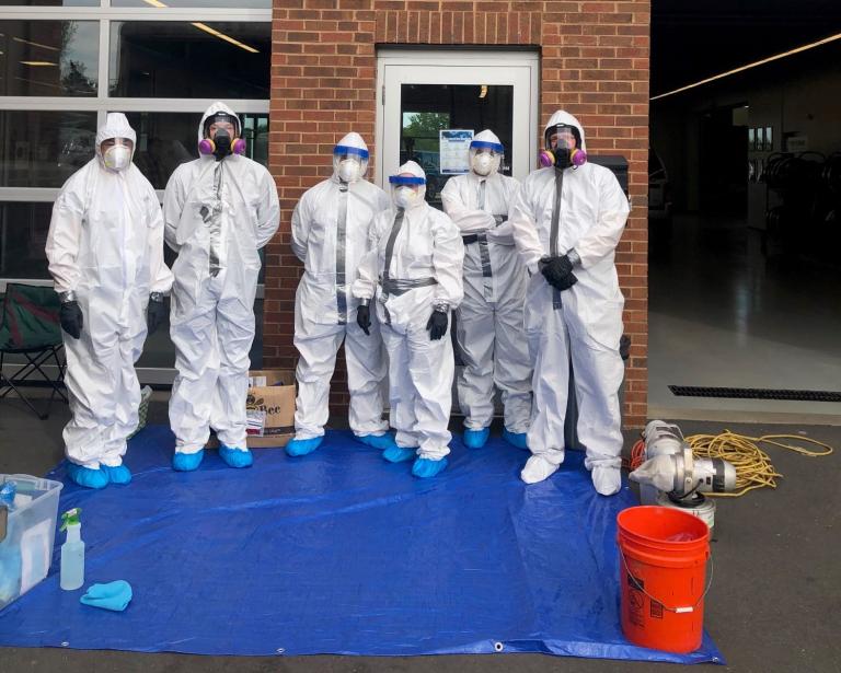 Photo of Bio-One team in work gear gathered for group photo outside in front of unnamed business building