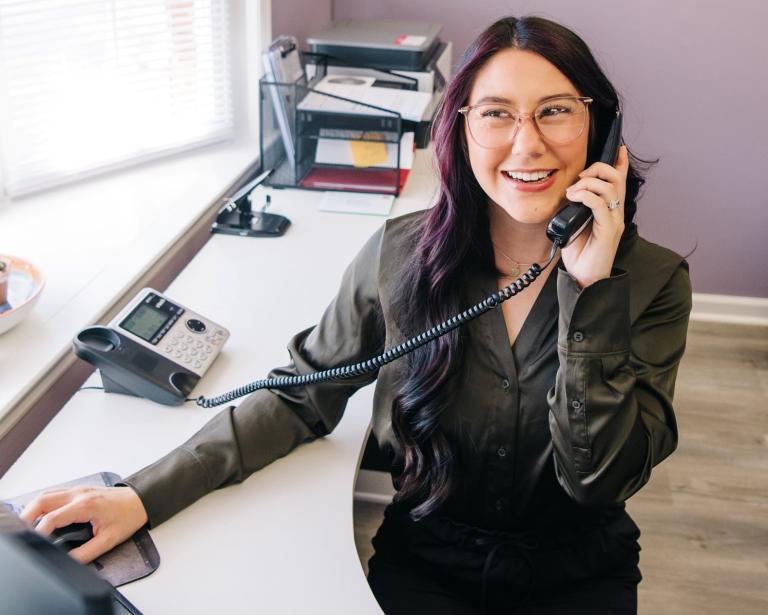 Photo of Cornerstone Family Chiropractic staff member working at desk and answering the telephone.