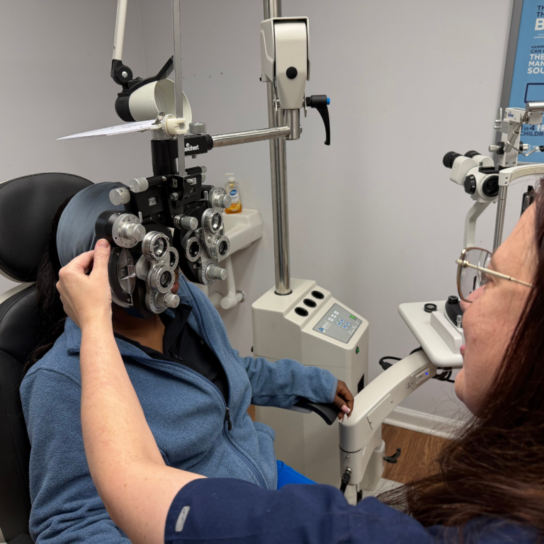 An eye doctor is using a phoropter with a patient - seeing which images appear clearer or less clear