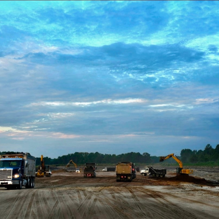 It's outside in a gravel/ sand area with several construction trucks and dump trucks